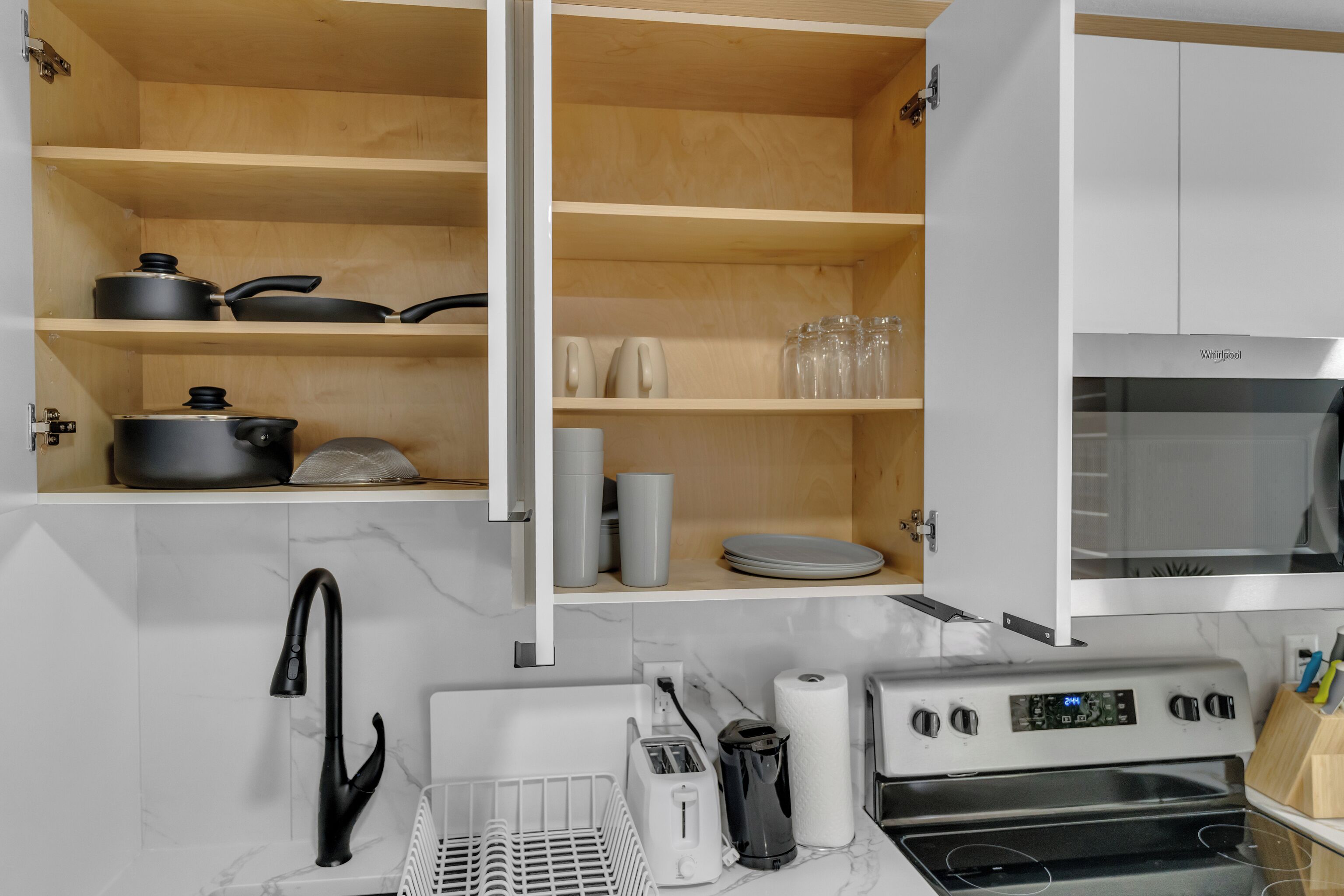 A kitchen with white cabinets, a stove, and a microwave.