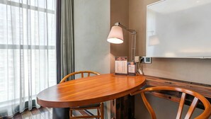 A conference room with a wooden table, two chairs, a whiteboard, and a lamp.