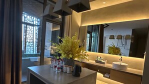 A modern bathroom with a large mirror, a sink, and a vase with yellow flowers.