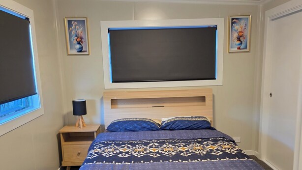 A bedroom with a bed, a nightstand, a lamp, and a ceiling light.