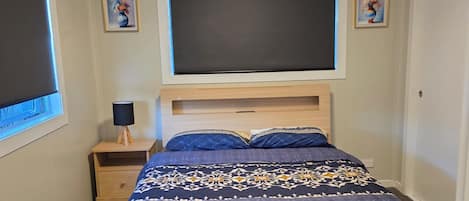 A bedroom with a bed, a nightstand, a lamp, and a ceiling light.