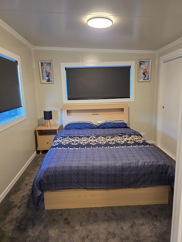 A bedroom with a bed, a nightstand, a lamp, and a ceiling light.