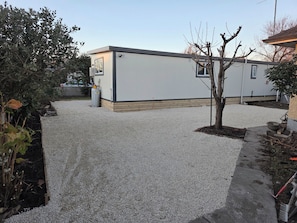 A building with a gravel driveway and a small tree.