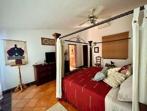 A bedroom with a four-poster bed, a ceiling fan, a television, and a decorative tapestry. - Casa Serena Vallarta/Perfect 3-BR house with AC, Private Pool & Near the Beach. (Puerto Vallarta)