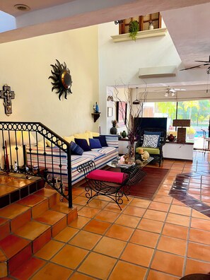A spacious living area with a staircase, a sofa, a dining table, and a view of the outdoors. - Casa Serena Vallarta/Perfect 3-BR house with AC, Private Pool & Near the Beach. (Puerto Vallarta)