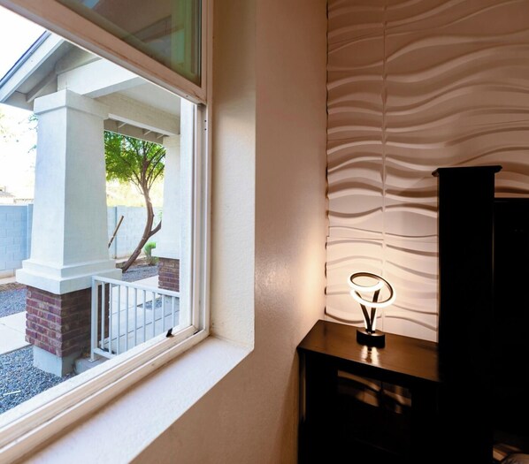 A room with a window, a wall with a textured pattern, and a small table with a light fixture. - NO FEES! Downtown Studio-style L/O, Night Security (Mesa)