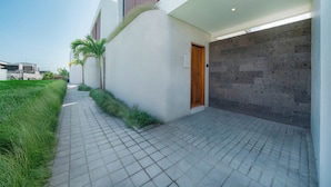 Um edifício moderno com um caminho pavimentado, uma porta de madeira e uma garagem com parede de pedra.