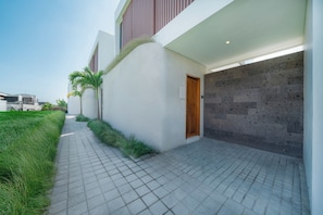 Un edificio moderno con un camino empedrado, una puerta de madera y un garaje con un muro de piedra.
