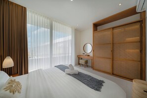 Una habitación de hotel con una cama grande, un escritorio, un armario y una ventana con cortinas translúcidas.