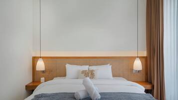 A hotel room with a bed, two bedside lamps, a wooden headboard, and a window with curtains.