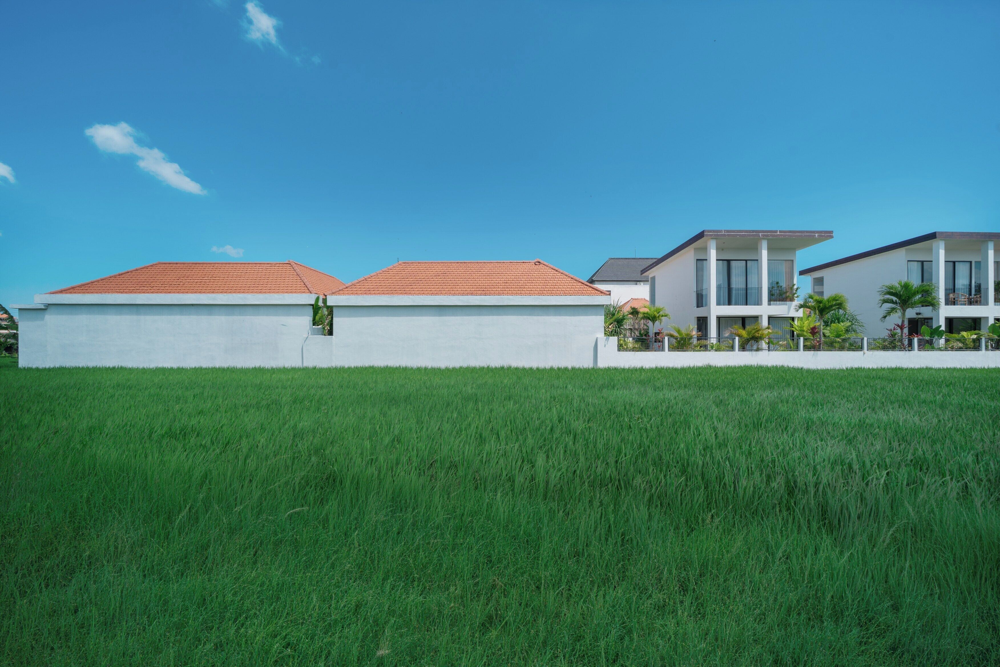 A modern residential area with two-story houses, a well-maintained lawn, and a clear blue sky.