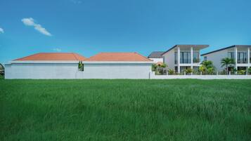 A modern residential area with two-story houses, a well-maintained lawn, and a clear blue sky.