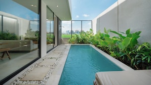Área moderna de piscina ao ar livre com vista desobstruída para o horizonte da cidade, cercada por vegetação exuberante e design minimalista.