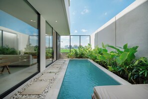 Un área de piscina moderna al aire libre con vistas despejadas al horizonte de la ciudad, rodeada de exuberante vegetación y un diseño minimalista.