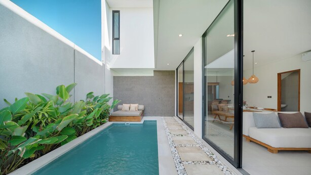 Uma área moderna com piscina ao ar livre, espaço de estar integrado e parede de vidro que dá para uma sala de jantar.