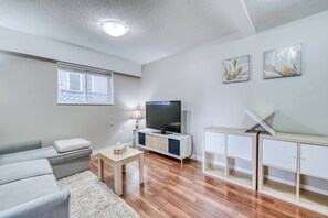 A living room with a sofa, a TV, a coffee table, and a cabinet. - Cozy Stay Near YVR | 1 Bed + Sofa Bed | Sleeps 4 (Vancouver)
