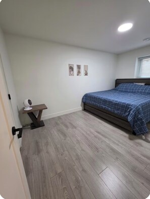 Un dormitorio con una cama, una mesita de noche con lámpara y un ventilador de pared.
