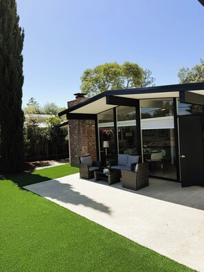 A modern outdoor patio with a glass enclosure, outdoor furniture, and a well-maintained lawn. - Modern Palo Alto Home -Perfect for Mid‑Term Stay (Palo Alto)