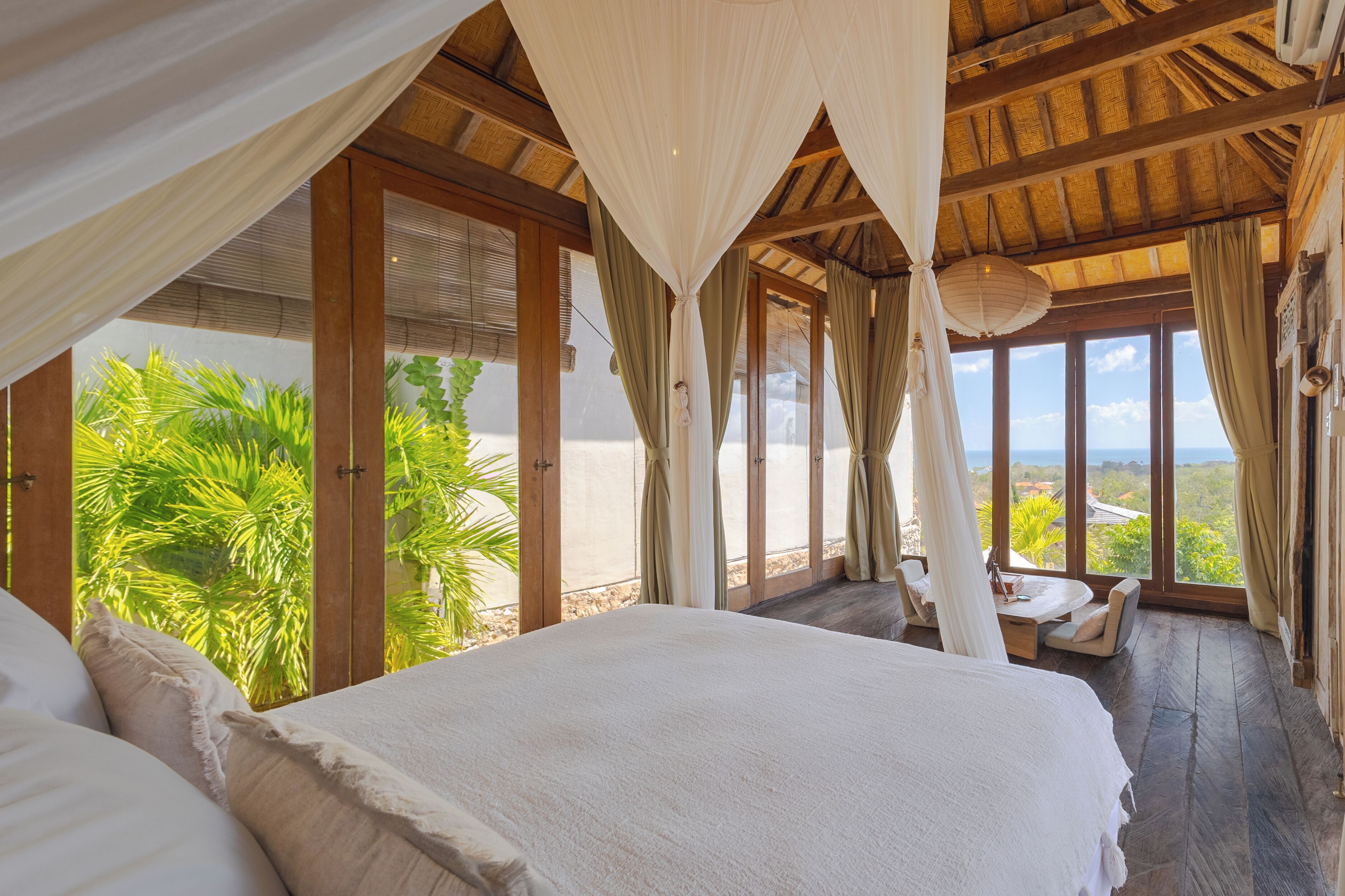 Un dormitorio con una cama grande, vigas de madera y vistas a la vegetación.