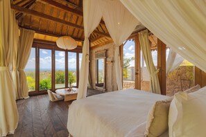 Une chambre dotée d’un grand lit, d’un plancher en bois et offrant une vue sur le paysage.