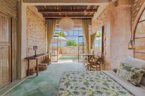 Una habitación con cama, una mesa, sillas, una lámpara colgante y vistas al exterior.