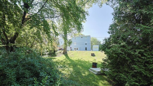 A residential property with a grassy yard, a tree, and a house in the background. - Renovated Lakefront 5BR • Near Colleges • Sunsets • Sleeps 12 (Worcester)