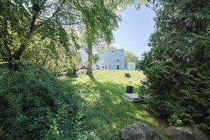 Una propiedad residencial con jardín césped, un árbol y una casa al fondo.