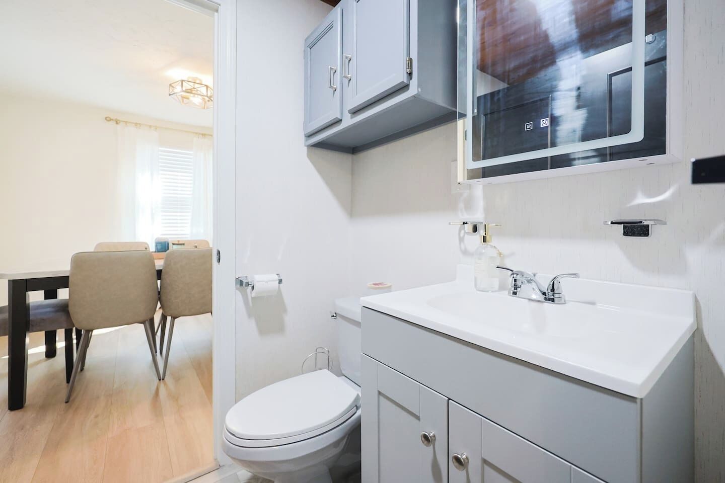 Een moderne badkamer met een wit wastafel, toilet en kast.