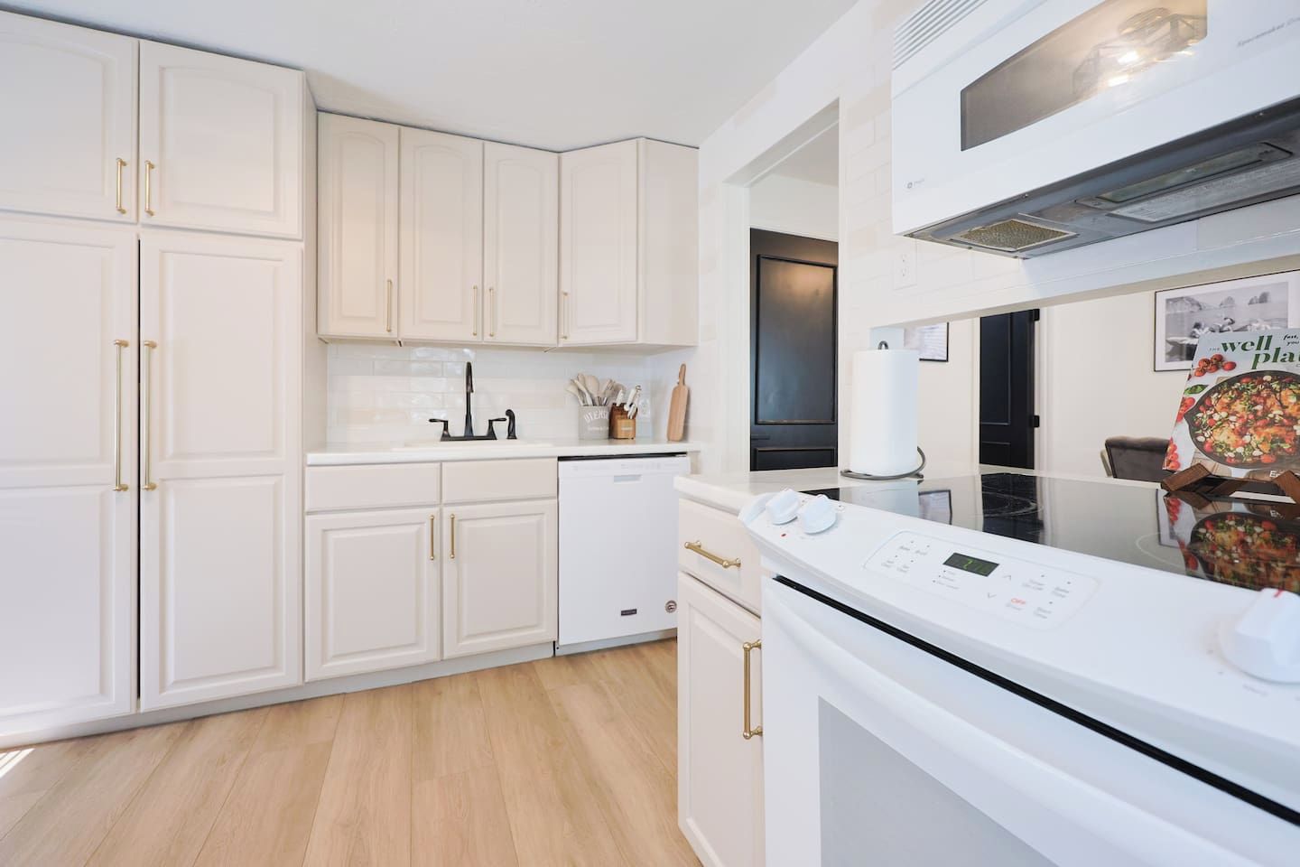 Una cocina moderna con armarios blancos, lavavajillas, estufa y microondas.