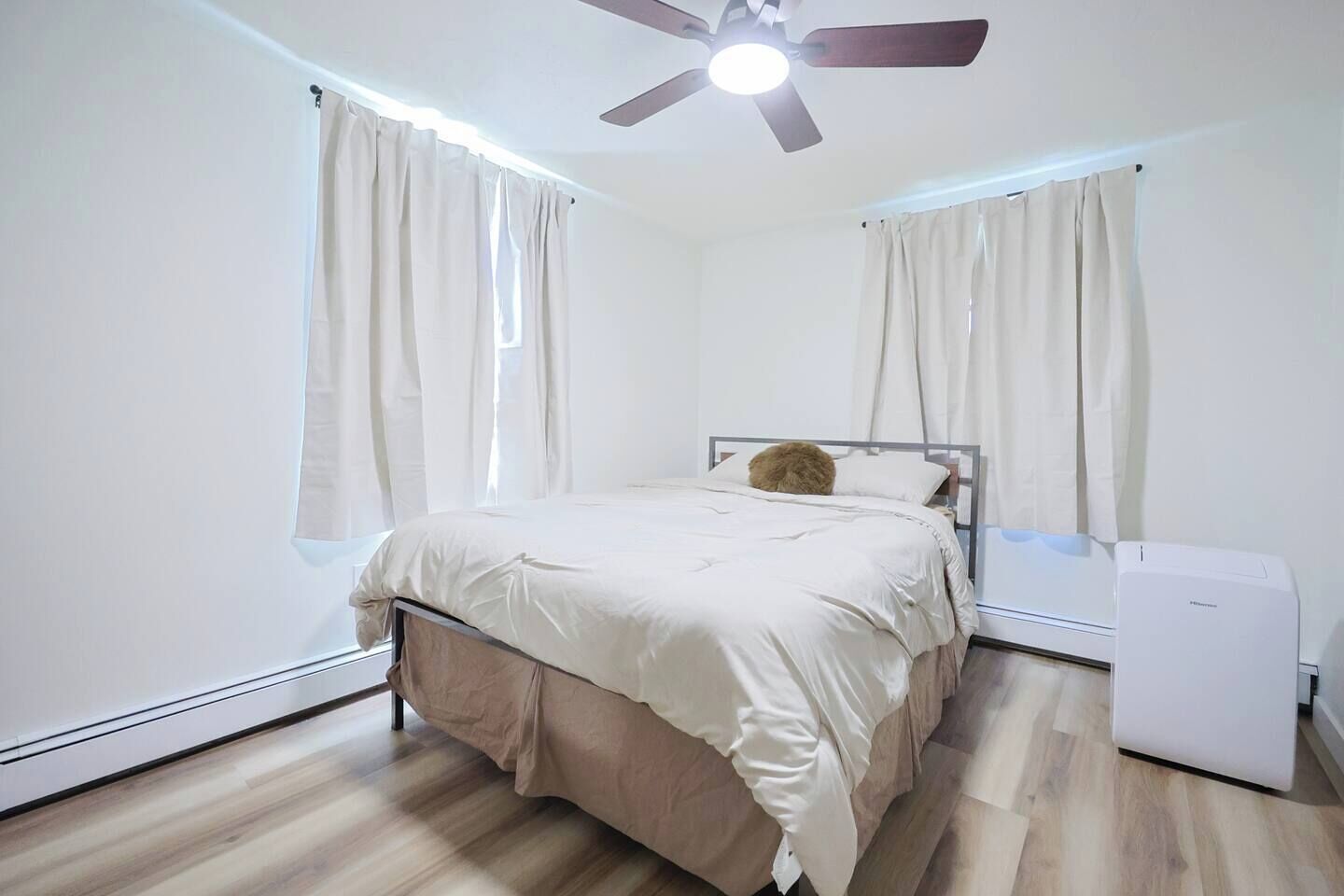 A bedroom with a bed, a ceiling fan, and a heater.