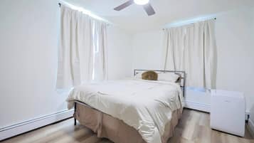 A bedroom with a bed, a ceiling fan, and a heater.