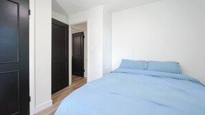 A bedroom with a bed, a door, and a hallway. - Renovated Lakefront 5BR • Near Colleges • Sunsets • Sleeps 12 (Worcester)