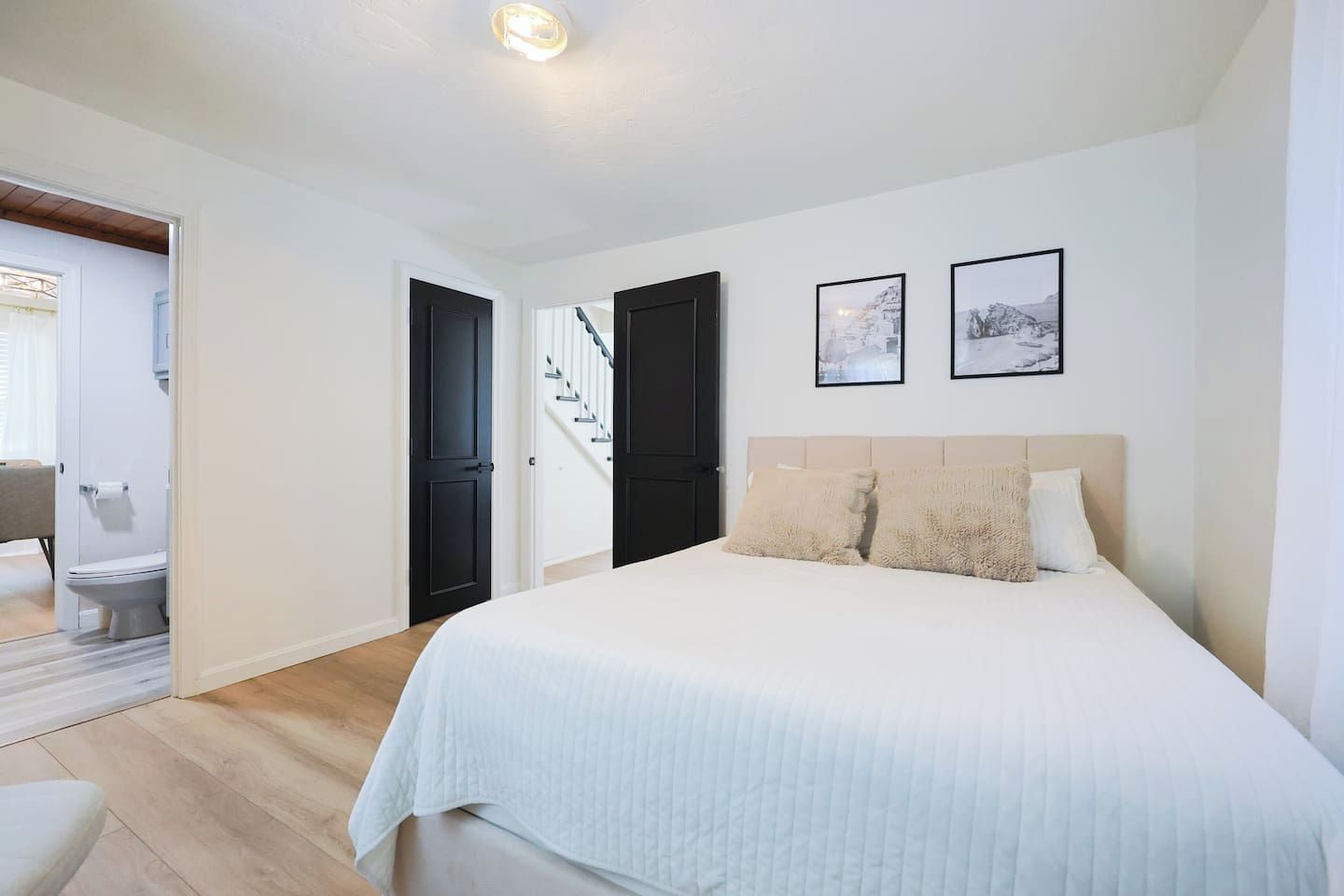 Un dormitorio con cama, una escalera y un baño visible a través de una puerta abierta.