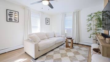 A modern living room with a sofa, a small table, and a ceiling fan.
