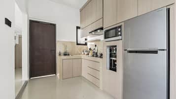 Cocina moderna con electrodomésticos de acero inoxidable, armarios de madera y un refrigerador inverter digital.