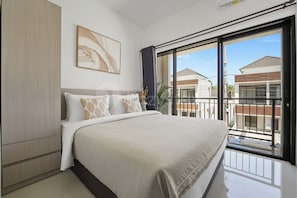 Ein modernes Schlafzimmer mit einem großen Bett, einem Bild an der Wand und Blick auf benachbarte Gebäude vom Balkon aus.