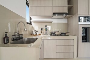 A modern kitchen with a stainless steel sink, a built-in stove, and wooden cabinets.
