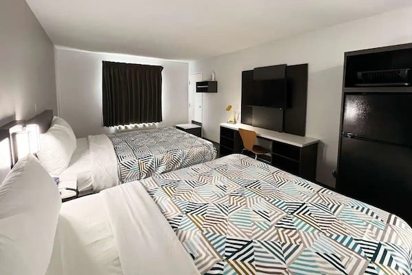 Ein Hotelzimmer mit zwei Betten, einem Schreibtisch, einem Fernseher und einem Kleiderschrank.