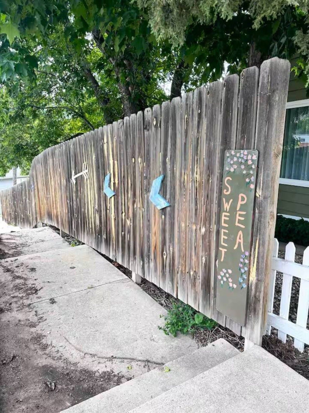 Une clôture en bois agrémentée d’éléments décoratifs et d’une enseigne sur laquelle on peut lire le mot « SWEET ».