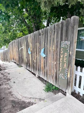 A wooden fence with decorative elements and a sign that reads 'SWEET.'