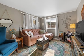 A living room with a sofa, armchair, and a small table with a lamp.