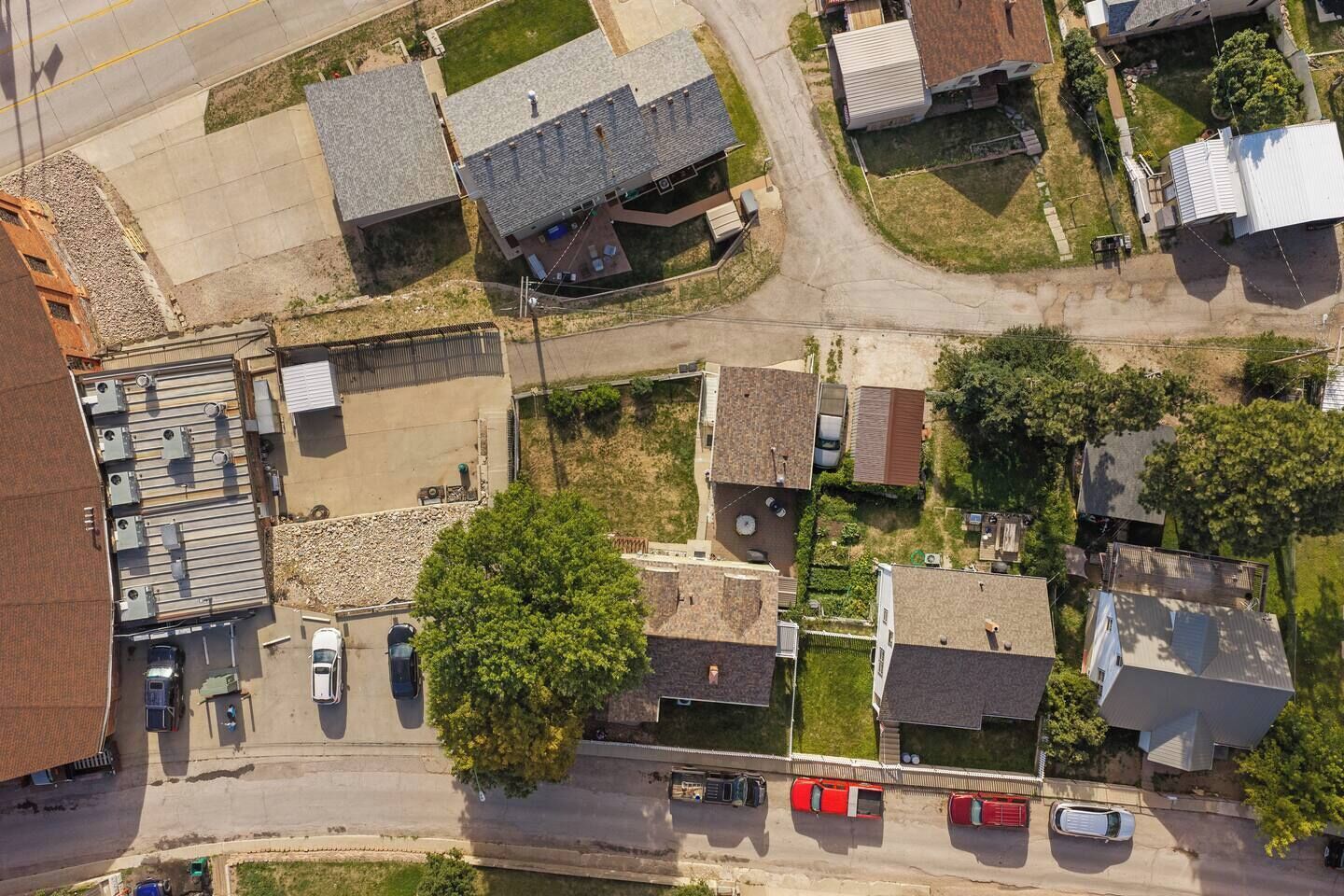 Vue aérienne d’un quartier résidentiel avec des maisons, un parking et un petit immeuble commercial.