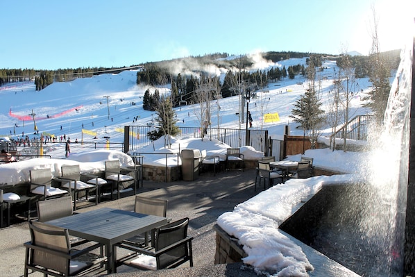 An outdoor seating area with tables and chairs, overlooking a snowy ski slope. - Ski-in/out one-bedroom at Grand Colorado Peak 8, pools, spa, sleeps 4 (Breckenridge)