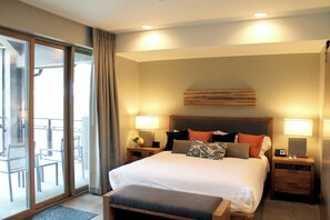 A hotel room with a large bed, two bedside tables, a wooden headboard, and a balcony with chairs. - Ski-in/out one-bedroom at Grand Colorado Peak 8, pools, spa, sleeps 4 (Breckenridge)