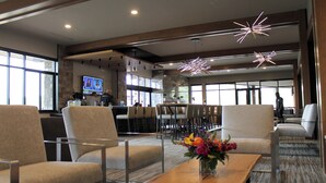 Een ruime lobby met moderne zitplaatsen, een bar en grote ramen die natuurlijk licht binnenlaten.