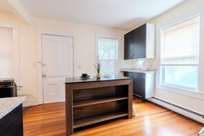 A kitchen with wooden flooring, a built-in dark wood cabinet, and a white door. - NEW - Boston/Cambridge/3BR/Near MIT + Newbury St (Cambridge)