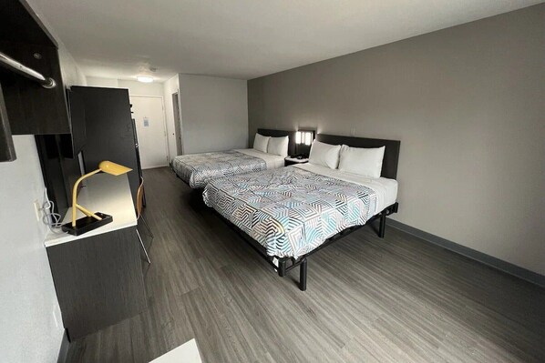 Ein Hotelzimmer mit zwei Betten, einem Schreibtisch mit Lampe und einem Kleiderschrank.