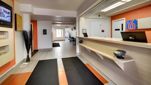 Un espace d’accueil moderne doté d’un téléviseur à écran plat, d’un comptoir de réception et d’un écran numérique affichant le chiffre 6.