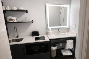 Une salle de bain moderne équipée d’un lavabo, d’un miroir et d’un four à micro-ondes encastré.