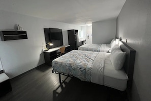 Une chambre d’hôtel avec deux lits, un bureau, une chaise, une télévision et un mini-bar.
